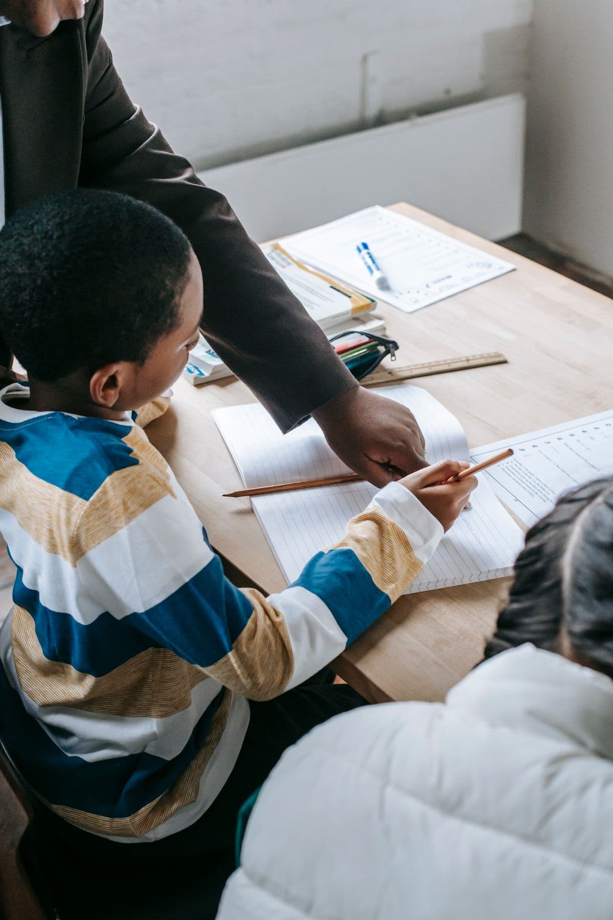 A teacher helping children with their schoolwork at a desk