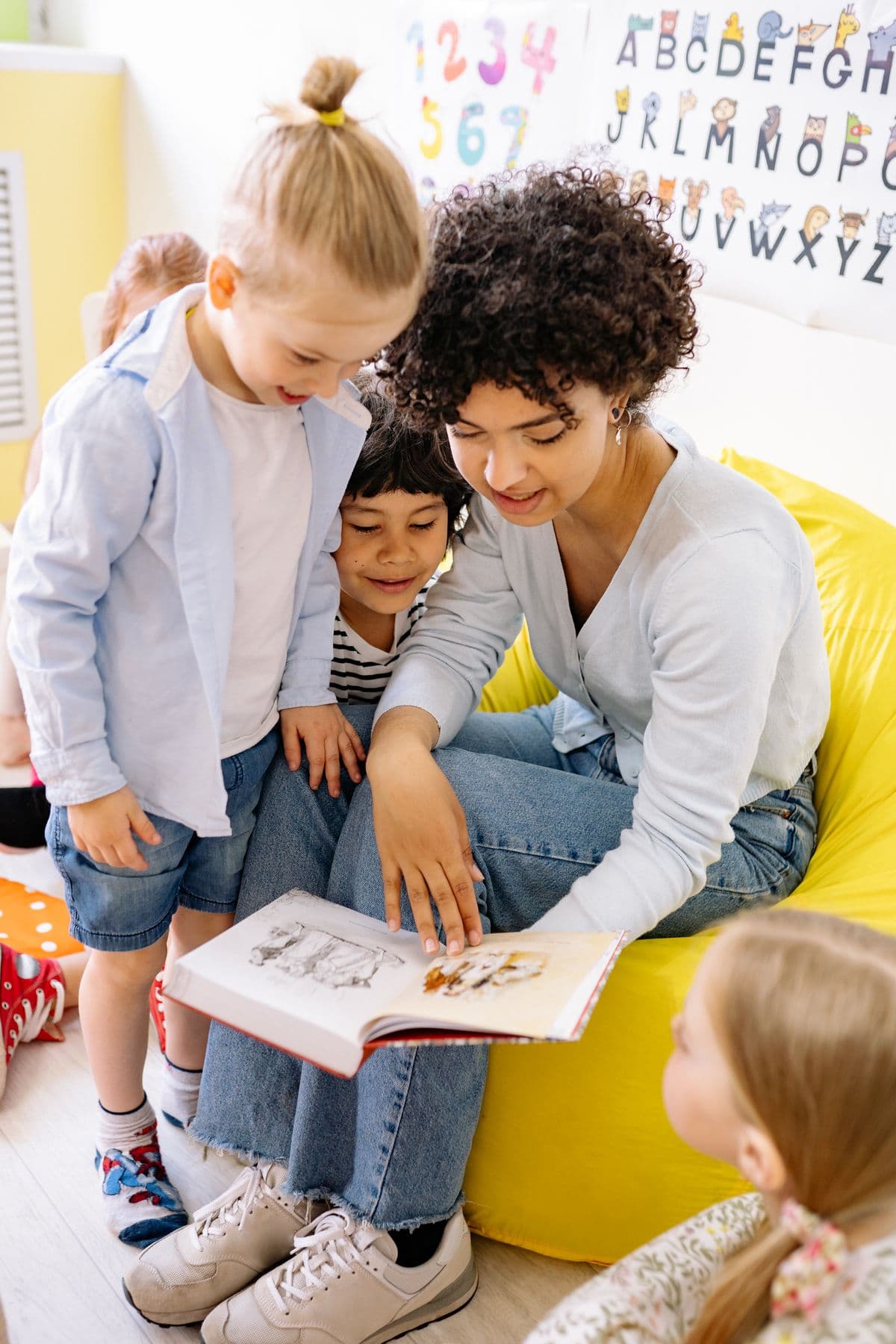 Children sharing a book with their teacher